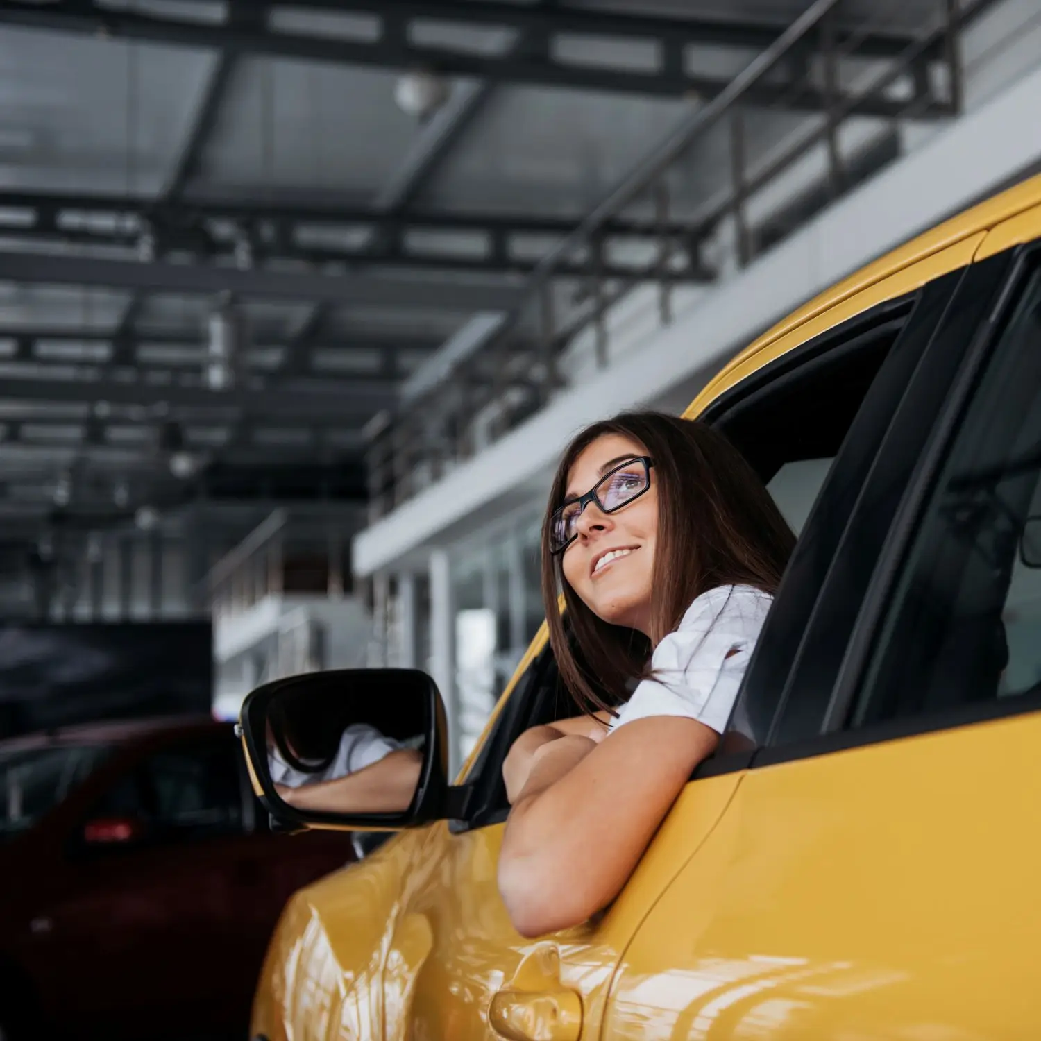 smiling woman inside a yellow car looking up 2026 01 09 00 39 43 utc.webp